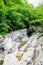 Massive chalk stones riverbed with wild river and pools formed by Okatse Waterfall in gorge of Satsikvilo, lush vegetation,