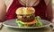 Massive Cheeseburger on a Plate in front of a dinner guest