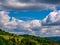 Massive clouds - Cumulus congestus or towering cumulus - forming in the blue sky over hilly landscape
