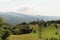 Massive electricity pole in nature, green vegetation covered mountains in background. high voltage electricity pillar