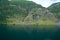 Massive geiranger fjord in norway seen from a cruise ship with light shining through the clouds and waterfall