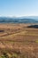 Massive hay field dry with a clear cut path mountain backdrop warm color bulgaria rural landscape sun day clear blue sky