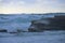 Massive ocean waves surge over rock outcrop