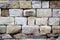 Massive a stone masonry with grey, light brown rectangular rocks. Erased adhesive mixture