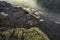 Massive structured steep stone wall with green moss and water