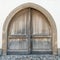 Massive winged wooden door in a stone wall with a wooden door arch