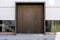 Massive wooden entrance door to modern white house with paving footpath in the city.