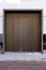 Massive wooden entrance door to modern white house with paving footpath in the city.