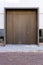 Massive wooden entrance door to modern white house with paving footpath in the city.