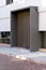 Massive wooden entrance door to modern white house with paving footpath in the city.