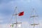 Mast of vintage mast wooden sailing ship for sea tours in port of Saranda, Albania with red state albanian flag with black double-