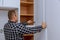 Master adjusts fixing the hinge of the kitchen cabinet door with screwdriver