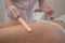 The master applies the anesthetic gel with a spatula to the woman& x27;s legs before laser hair removal. Permanent hair
