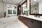 Master bathroom interior in luxury modern home with dark hardwood cabinets, white tub and glass door shower