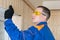 Master in a blue uniform and black gloves, fixing a wooden clapboard to insulate the balcony, close-up