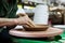 A master ceramist with 13 years of experience makes plate from red clay on a potter`s wheel, on a sheet of particle