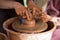 Master class for child. Teacher hands show to kid how make ceramics dishes on potter wheel. Artist works with clay