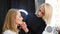 Master cosmetologist tints the contours of the lips of a female client.