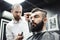 Master cuts hair and beard of men in the barbershop, hairdresser makes hairstyle for a young man.