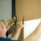 The master fastens the plywood to the cabinet using a hammer and nails.