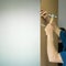 The master fastens the plywood to the cabinet using a hammer and nails.