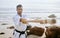 A master is a full-time student. Shot of a young martial artist practising karate with a wooden katana on the beach.