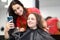 Master hairdresser with client look at smartphone screen in beauty salon.