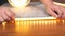 The master installs a luminous LED strip close-up, hands stick tape on a wooden surface