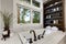 Master modern bathroom interior in luxury home with dark hardwood cabinets, white tub and glass door shower