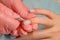 Master pink gloves makes the manicure on the nails of a young girl,