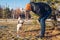 Master playing with pug dog outdoors. Animal jumping to bite mittens. Man walking pet in snowy winter park.