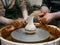 The master Potter helps the child to paint a clay jug with white paint on a modern Potter`s wheel with an electric drive.