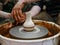 The master Potter helps the child to paint a clay jug with white paint on a modern Potter`s wheel with an electric drive.