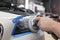 Master repairman polishing headlights of car in workshop using machine closeup.