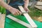 The master sharpens the wooden panel with an electric grinder on a Sunny day in the garden. Dimensioning