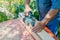 The master sharpens the wooden panel with an electric sander on a Sunny day in the garden. Danger. Violation of safety regulations