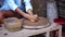 Master starts girl continues making clay pot on potter wheel