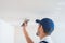 A master in uniform puts putty on the caps of self-tapping screws for fixing plasterboard sheets on the ceiling