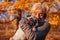 Master walking pug dog in autumn park. Happy woman hugging pet. Friendship between human and animal