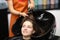 Master washes her hair in sink for client in hairdressing salon