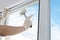 Masterâ€™s hand in protective gloves, fixes a double-glazed window with a plastic baseboard, hammering it with a rubber mallet,