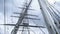 Masts and cables of ship on background of cloudy sky. Action. Towering masts with many intertwined cables and ropes of