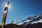 Masts with prayed flags in sunshine with snowy mountain in background