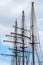 masts and rigging of a historic three-master sailing ship against the cloudy sky, travel and voyage concept, vertical