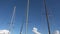Masts of sailing boats moving slowly in the wind in front of a sky