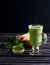 Matcha green tea latte beverage in glass cup on dark wooden back