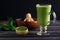Matcha green tea latte beverage in glass cup on dark wooden background