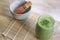 Matcha Green Tea Smoothie with Stone Bowl and wooden whisk on bamboo mat on table