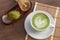 Matcha latte art heart shape on top on wooden table with some gr