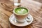 Matcha latte green milk foam cup on wood table at cafe. Trendy powered tea trend from Japan